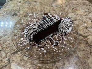 Delicious chocolate cake slice with whipped cream and chocolate drizzle.