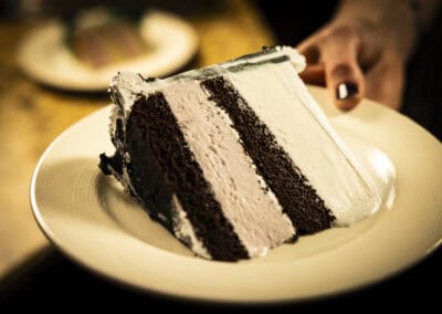 Chocolate layer cake with white frosting on a white plate. Delicious chocolate layer cake with creamy white frosting, perfect for celebrations at Angelo's Rest.