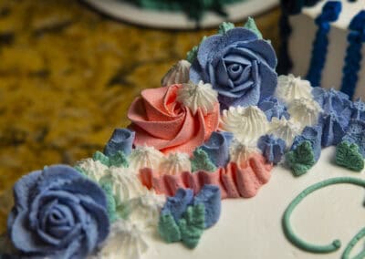 Elegant birthday cake with blue roses and colorful frosting decorations. Beautiful birthday cake decorated with blue roses and pastel frosting.