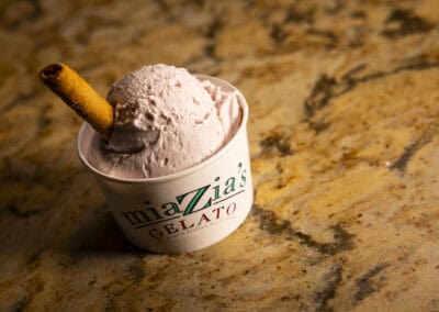 Delicious Gelato at Angelo's Creamy gelato with a cookie stick in a branded cup.