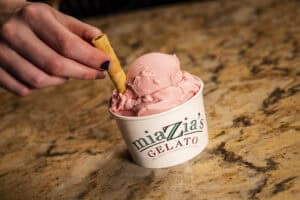 Strawberry gelato in a cup with a wafer stick, served at Angelo's Restaurant.