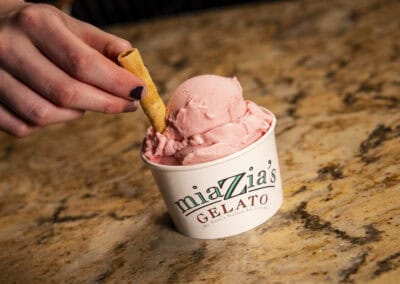 Creamy strawberry gelato served in a cup at Angelo's Restaurant. Strawberry gelato in a cup with a wafer stick, served at Angelo's Restaurant.
