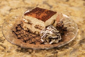 Delicious chocolate tiramisu served with whipped cream and chocolate drizzle.