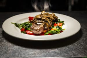 Juicy grilled steak topped with savory mushroom sauce on a bed of greens.