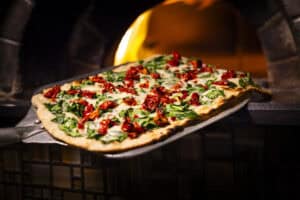 Margherita pizza with fresh basil, mozzarella, and tomatoes baking in a wood-fired oven.