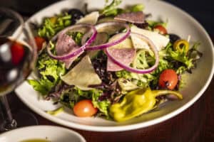 Healthy mixed greens salad with cherry tomatoes, sliced onions, and cured meat. Perfect for a light,.
