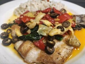 Delicious fish dish with vegetables and olives, perfect for a healthy meal at Angelo's Restaurant.