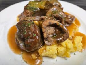 Gourmet meat dish with rich gravy served with polenta at Angelo's Restaurant.