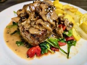 Juicy grilled steak topped with savory mushroom sauce and fresh vegetables.