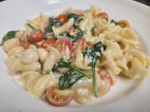 Delicious pasta dish featuring cherry tomatoes, spinach, and creamy sauce, served at Angelo's Restau.