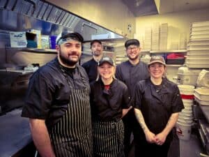 Happy kitchen staff preparing delicious meals in the restaurant's busy kitchen.
