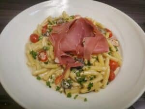 Delicious pasta dish featuring cherry tomatoes, fresh herbs, and thin slices of prosciutto. Perfect.