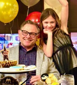 Happy man and girl celebrating retirement with balloons and cake.